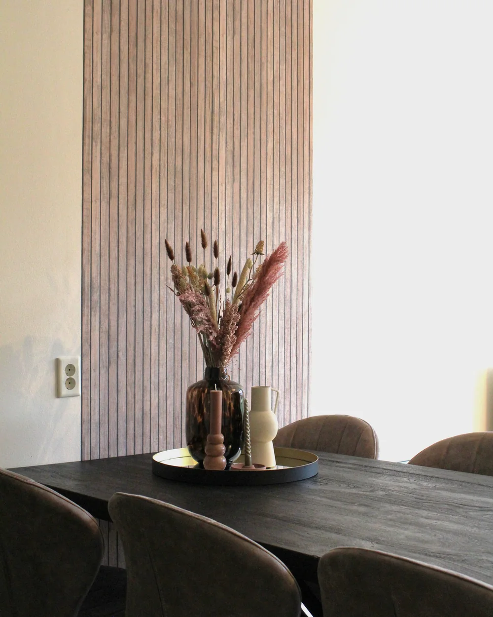 Mesa de comedor de madera maciza con sus sillas, contra un muro de listones